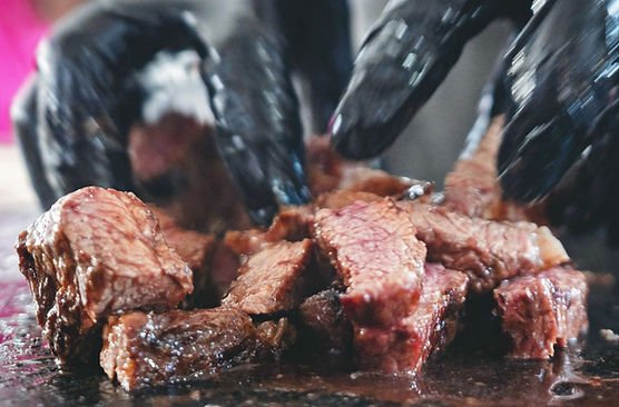Cortes de carne sendo preparados com luvas pretas