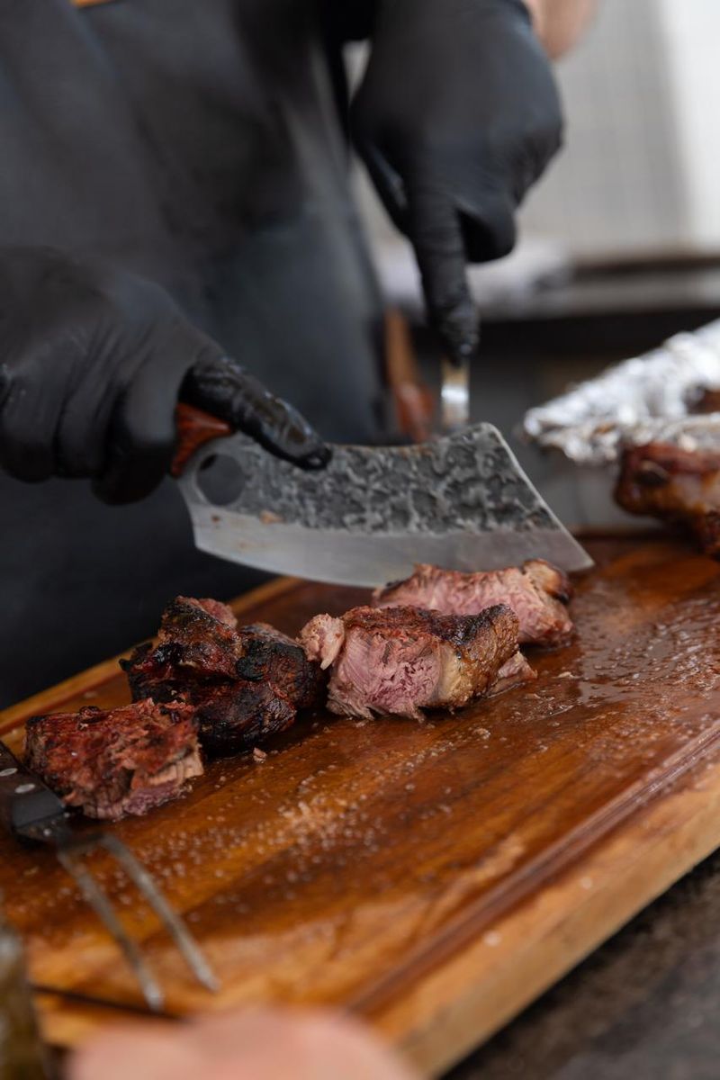 Cutelo e garfo sobre uma tábua de madeira com carne cortada